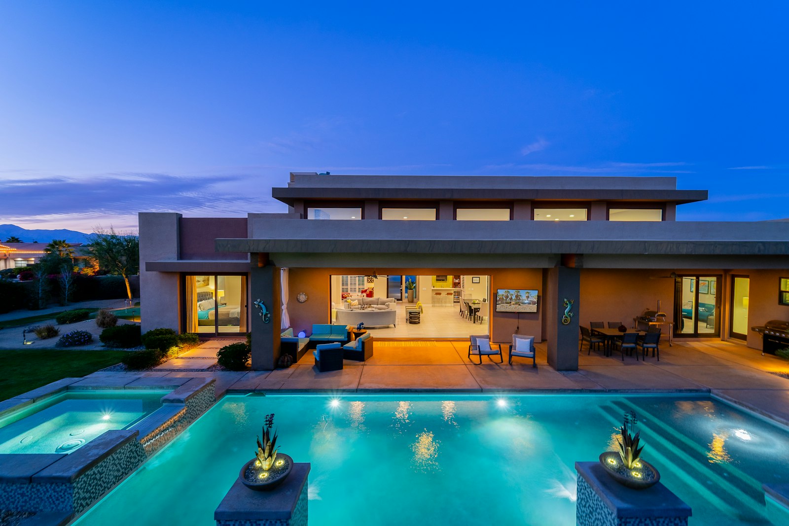 Modern luxury home exterior at dusk with warm interior light